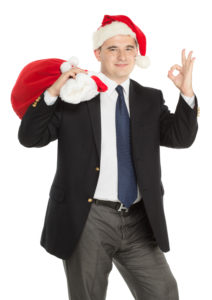 businessman headed to corporate holiday party with Santa hat and presents