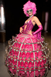 mardi gras entertainer with pink and purple dress and drink servers on the skirt