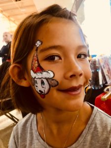 girl with holiday face painting on cheek at holiday party