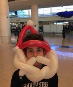 child with balloon sculpture that makes him look like santa claus