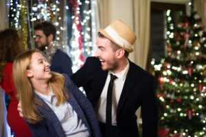 small office holiday party with man and woman laughing in front of Christmas tree