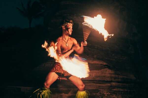 A skilled fire performer in traditional attire captivates with fiery artistry at night.